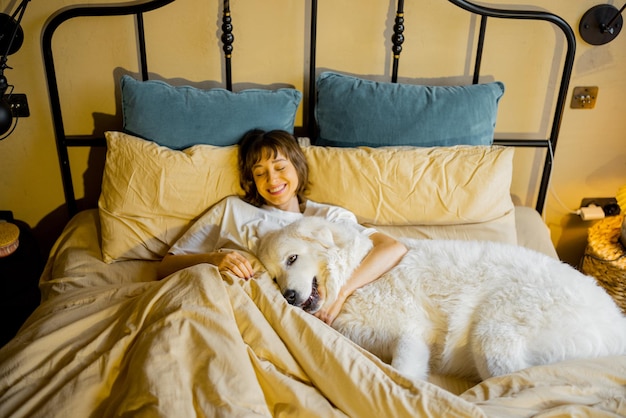 Woman sleeps with her huge and cute dog in bed