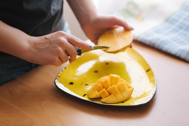 Woman slice mandgo on yellow plate Fresh exotic fruit