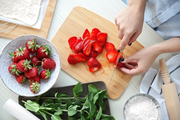 Woman slicing strawberries for dessert in kitchen