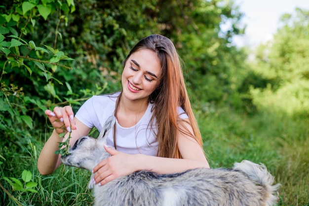 Woman and small goat green grass Farm and farming concept Village animals Girl play cute goat Feeding animal Protect animals Veterinarian occupation Eco farm Love and care Animals law