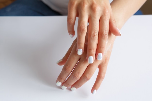 Woman smearing soft moisturizer on hands skin