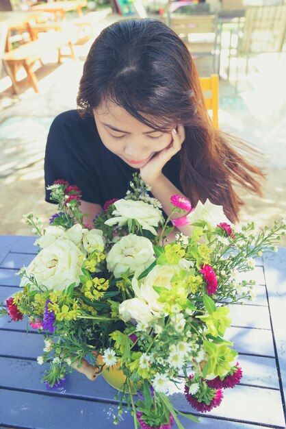 写真 テーブルで花の香りを嗅ぐ女性