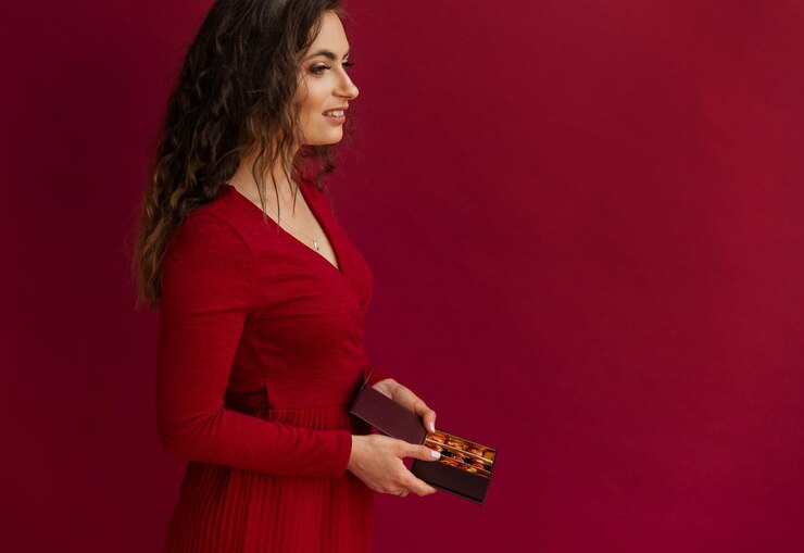 Woman smelling holding chocolate artisan bonbons and looking at side on red background
