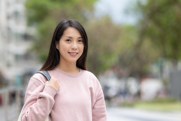 여자 는 카메라 에 미소 짓고 거리 에 서 있다