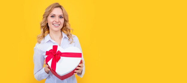 Woman smile hold present heart box on yellow background woman
isolated face portrait banner with mock up copy space