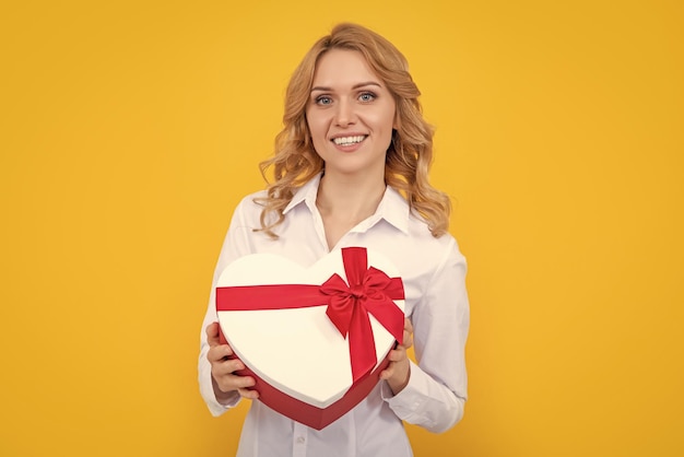 Woman smile hold present heart box on yellow background