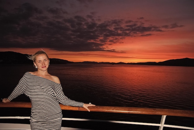 Woman smile on ship deck on dramatic sky over sea in Bergen Norway Happy woman enjoy sea travel in evening Sunset or sunrise Summer vacation on sea Travel by water Adventure and wanderlust