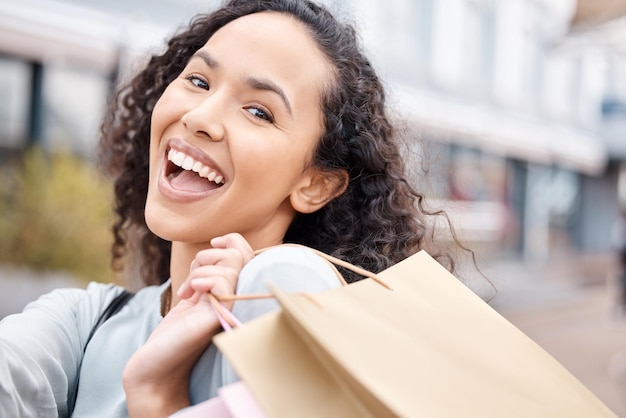 Woman smile with bags after shopping sale at retail store or shop in town mall Female customer happy after retail therapy with gift bag in street after buying products at shopping centre in city