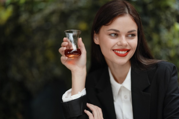 通りのトルコのガラスのカップからカフェで茶を飲む歯で笑顔の女性