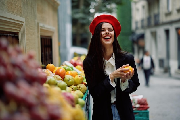 女性は歯で微笑む観光客が果物や野菜を持って市内の市場を歩き、商品を選ぶ、スタイリッシュでファッショナブルな服と化粧、春の散歩旅行