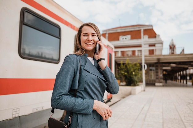 写真 駅で女性が笑顔で携帯電話で話す