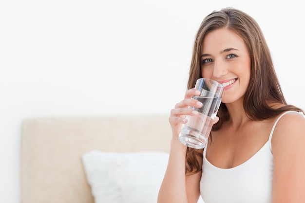 Woman smiles as she holds a glass to her mouth