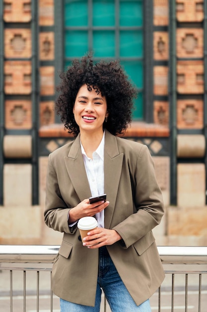 Woman smiles happy with a mobile phone in the hand