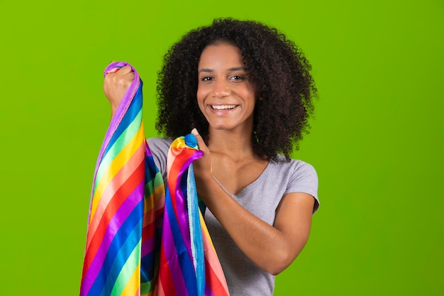 A woman smiles and holds a rainbow cloth in her hand.