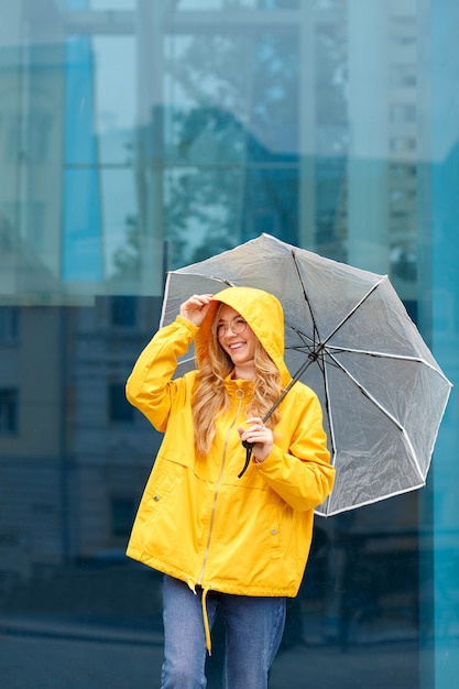 Woman smiles in a raincoat with an umbrella on a blue background