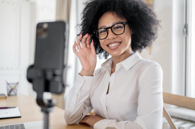 A woman smiles video communication chat on the phone online communication works the screen looks into the camera