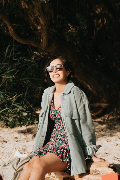 Женщина улыбается на пляже, используя летнюю концепцию солнцезащитных очков