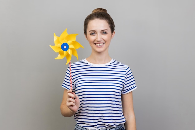 Woman smiling carefree and holding paper windmill pinwheel toy on stick