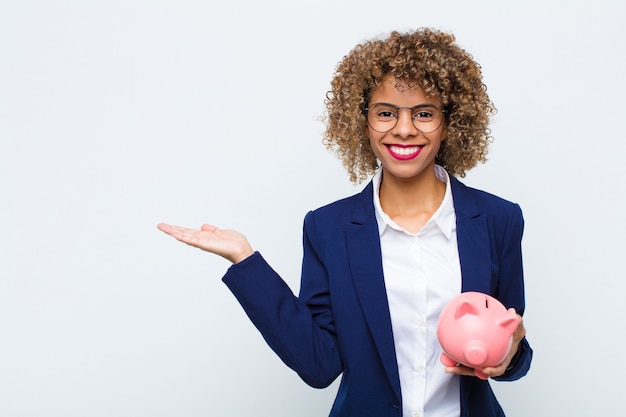 woman smiling cheerfully, feeling happy and showing a concept in copy space with palm of hand