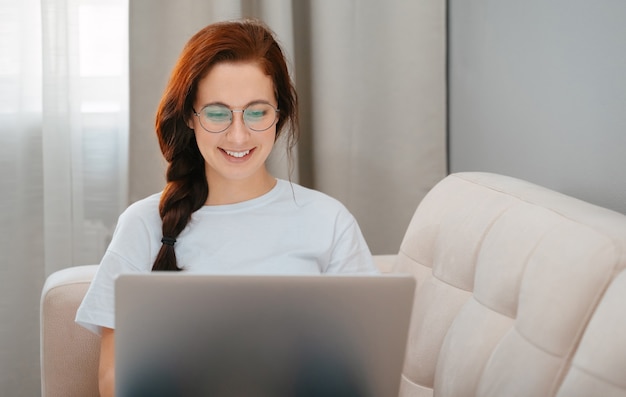 La donna sorridente comunica online attraverso un computer portatile nel concetto di impostazione domestica ordini online e formazione