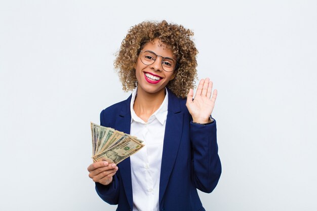 woman smiling happily and cheerfully, waving hand, welcoming and greeting you, or saying goodbye