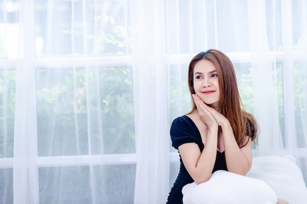 A woman smiling happily In the white bedroom The concept of living a happy life