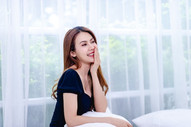 A woman smiling happily In the white bedroom