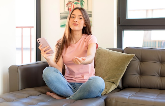 woman smiling happily with friendly, confident, positive look, offering and showing an object or concept