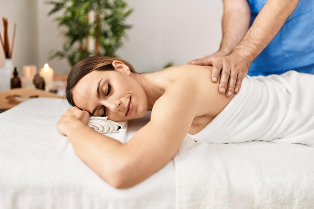 Photo woman smiling happy reciving back massage at beauty center
