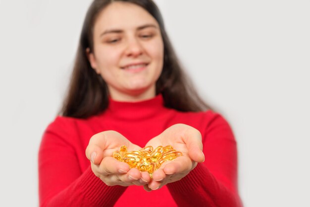 Foto una donna sorridente tiene tra i palmi delle mani una manciata di capsule di olio di pesce