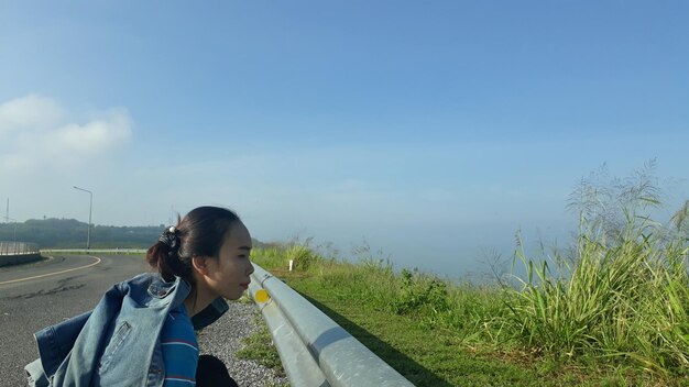 写真 空の向こうの畑の真ん中に道路で笑顔の女性