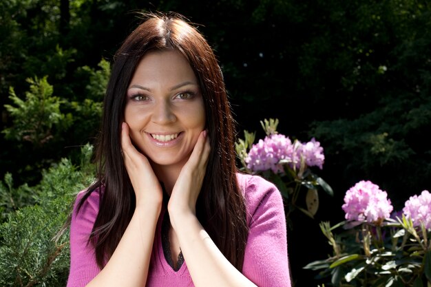 Woman smiling outdoors with some flowers