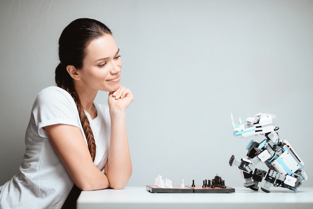 女性は笑顔でロボットとチェスをします。
