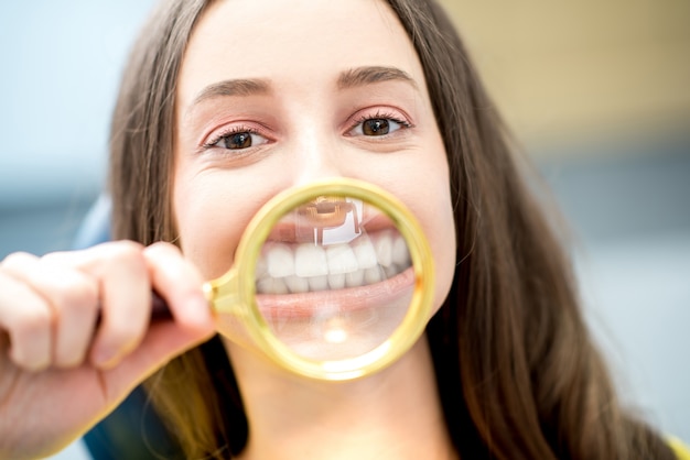 Woman smiling through the magnifying glass sitting at the dental office