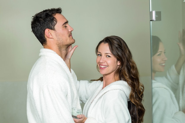 Woman smiling while applying moisturizer on manâ€™s face