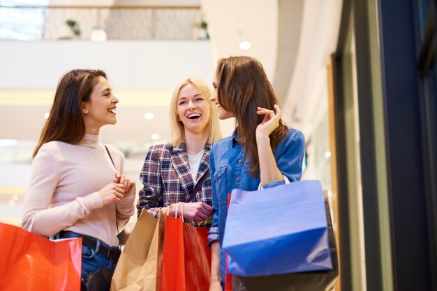 ショッピングバッグを抱えて店に立っている女性が微笑んでいます