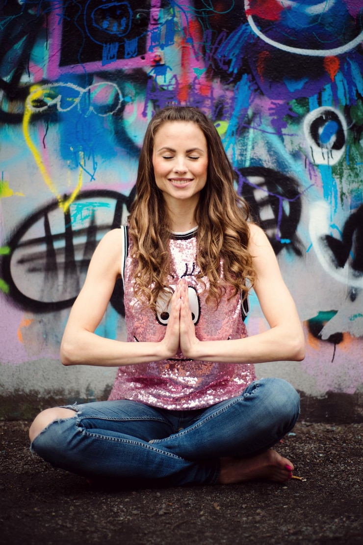 Photo woman smiling while meditating against graffiti wall