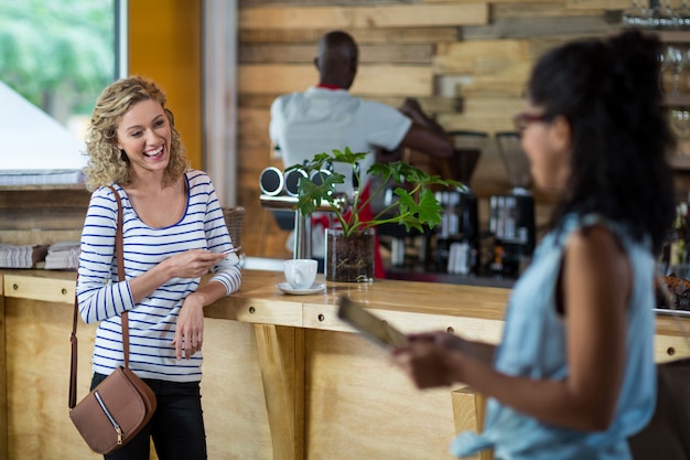 Photo woman smiling while using mobile phone at counter