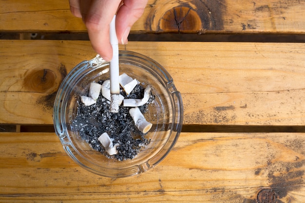 Photo woman smoking a cigarette holding a burning filter tip in her hand.