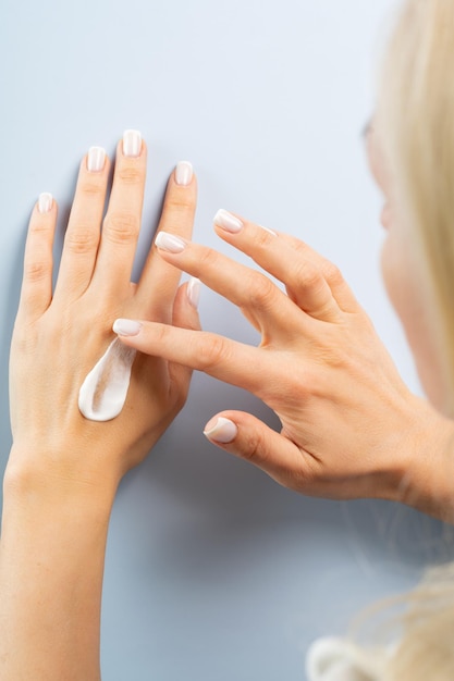 Woman smudging hand or body cream on her hands body care concept