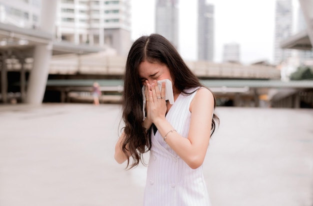 Woman sneeze on street because pollutionYoung female got nose allergy