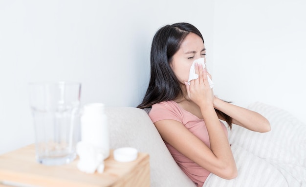 Woman sneezing on bed