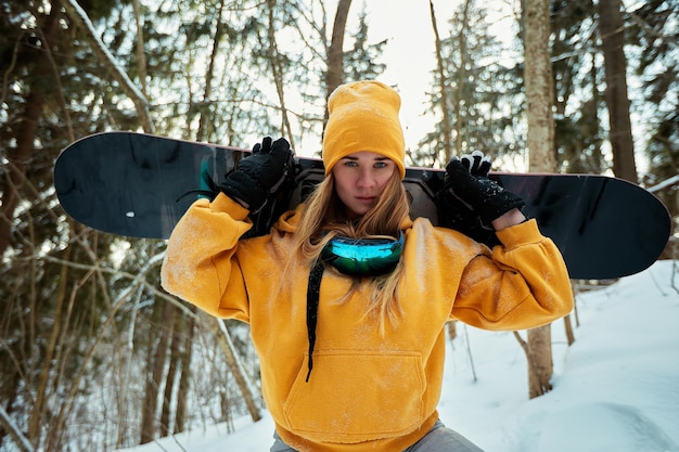 Woman snowboarder in bright suit in a sports glasses holds a snowboard Extreme sports Leisure