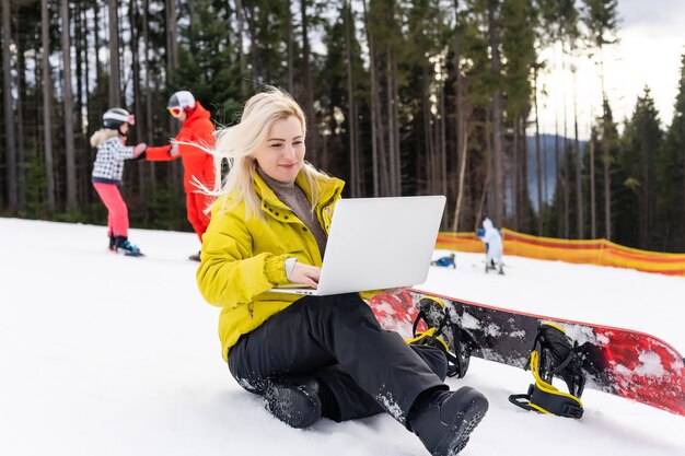 woman snowboarder working laptop in winter mountains