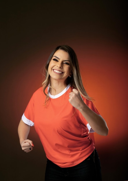 Woman soccer fan cheering for her favorite club and team world cup orange background