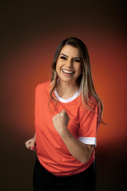 Woman soccer fan cheering for her favorite club and team world cup orange background