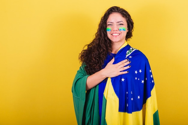 Woman soccer fan fan of Brazil World Cup singing the national anthem hand on chest