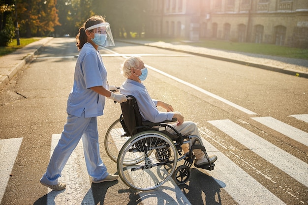 Woman social worker with elderly man walking in the city