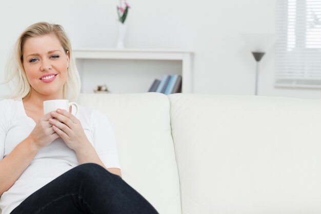 コーヒーを飲むソファの女性