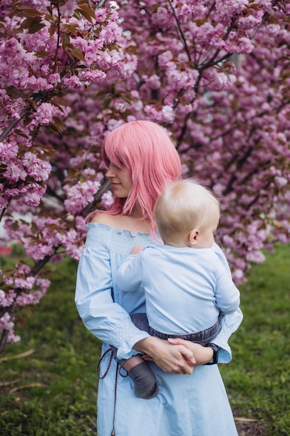 Woman and son in nature playing at spring park Little boy and mother have a good time on weekend activity in the blooming Sakura gardens